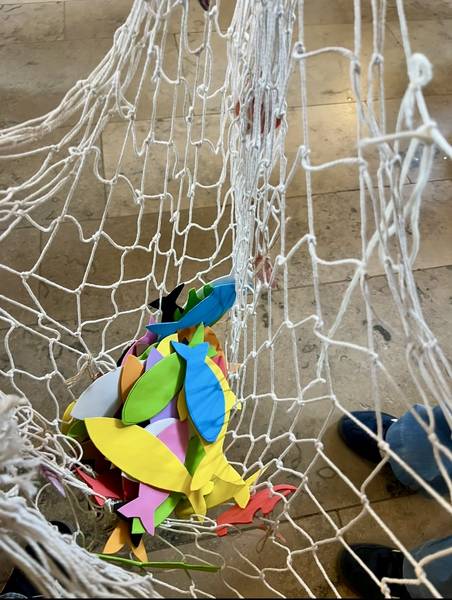 Bunte Fische aus Moosgummi liegen in einem Netz.
